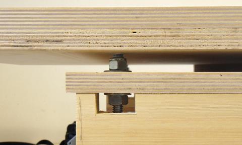 Two nuts on the studs clamp around a piece of plywood on the jointer's 